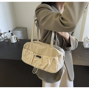 Detail of beige pleated shoulder bag with drawstring pocket and smooth canvas texture