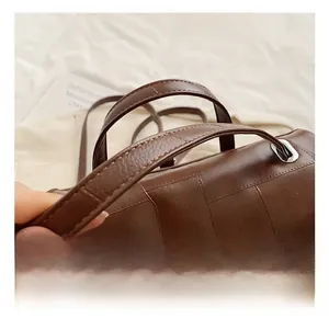 Detail of dark brown quilted leather handbag featuring silver twist lock and comfortable handle