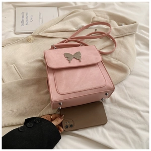 Détail d'un sac à main en cuir rose avec fermoir papillon argenté et référence de taille