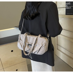 Detail of light beige ruched shoulder bag showing a drawstring design and side-carrying view