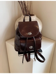Mini mochila retro de cuero café oscuro con cierre de giro en pedestal blanco