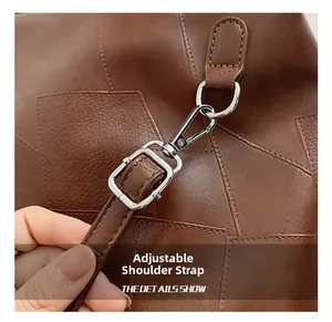 Close-up of adjustable shoulder strap on brown leather backpack with silver metal buckle