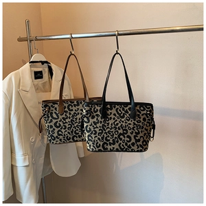 Detail of leopard print tote bags in brown and black straps with woven texture