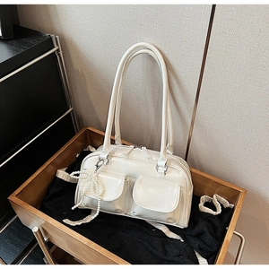 Detail of off-white Boston bag with front utility pockets and a pearl bow pendant
