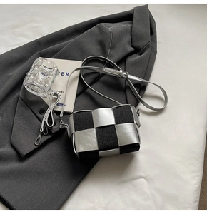 Close-up of silver woven leather crossbody bag featuring black textured fabric stitching