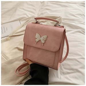 Détail d'un sac à main en cuir rose avec une grande boucle papillon en métal argenté