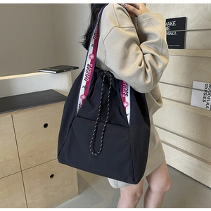 Vista de detalle del bolso de nailon negro con cordón y correa estampada ancha