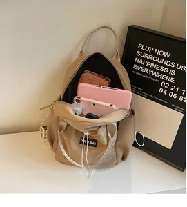 Interior storage view of a khaki nylon backpack showing space for tablet and bottle
