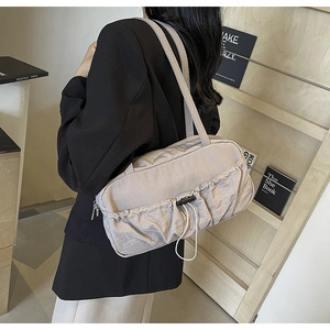 Detail of taupe pleated underarm bag with functional bungee cord and zipper texture
