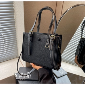 Nahaufnahme einer schwarzen Totebag aus Leder mit weißen Kontrastnähten und goldener Hardware