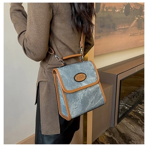 Detail of vintage faux suede handbag with denim texture and brown leather piping
