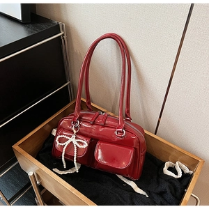 Detail of dark red patent leather Boston bag with pearl bow and front pockets