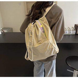 Detalle del bolso tote caqui con cinta de logo púrpura y correas tejidas para el hombro