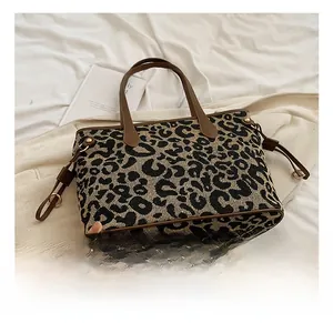 Close-up of leopard print woven tote bag featuring premium brown leather handle and gold hardware