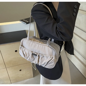 Detail view of stylish pleated nylon shoulder bag with drawstring pocket in off-white finish