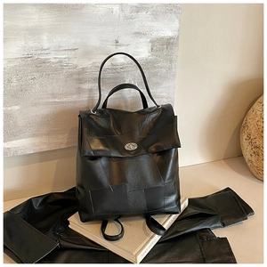 Detail of black patchwork leather backpack with silver oval swivel lock on a book