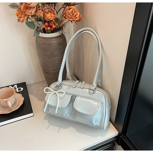 Close-up of light blue patent leather Boston bag with pocket details and pearl bow charm