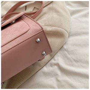 Détail du sac en cuir PU rose avec texture tissée et clous de protection en métal argenté