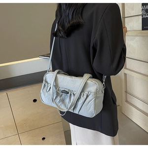 Detail of light blue pleated shoulder bag featuring drawstring design and nylon texture