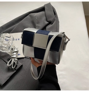 Detail of silver metallic and blue denim woven checkerboard crossbody bag with metal buckle