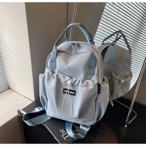 Detailed mirror view showing blue nylon backpack with drawstring pockets and dual handles