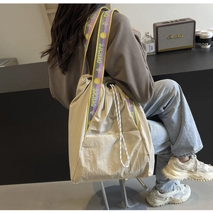 Detalle del bolso tote de lona beige con correa floral morada y cierre de cordón