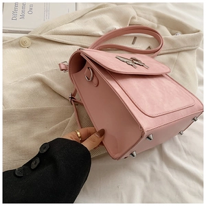 Détail du sac en similicuir rose avec boucle papillon argentée et clous de protection