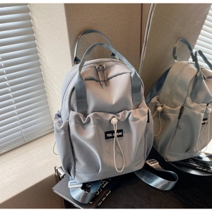 Detail of light blue nylon backpack with adjustable straps and YOU JI BEAR logo label