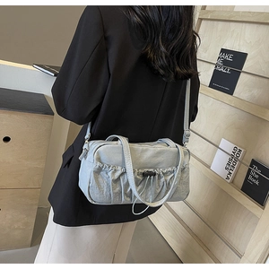 Macro detail of the light blue pleated shoulder bag featuring drawstring closure texture