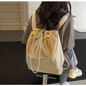 Vista trasera de una modelo con mochila de lona beige con cordón y bordado floral