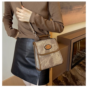 Detail of vintage suede texture and NICE FASHION logo on brown crossbody handbag