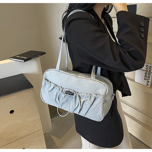 Detail of grey-blue shoulder bag featuring ruched nylon texture and drawstring pocket