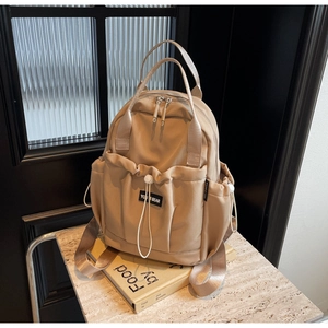 Detail of khaki nylon backpack with multi-pocket storage on marble table with books