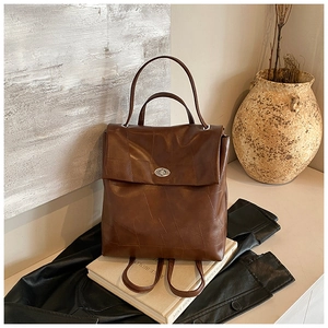 Detail of a dark brown patchwork backpack with matte leather texture and silver buckle