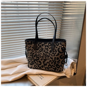 Close-up of leopard print tote bag with black leather handles and metal ring details