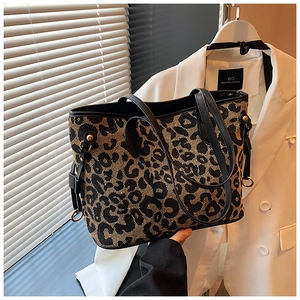 Detailed side view of leopard print tote bag with black handles and gold hardware accents