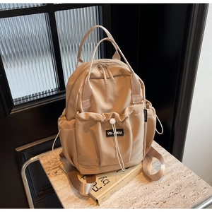 Detail of beige nylon backpack with drawstring pocket and sturdy double top handles