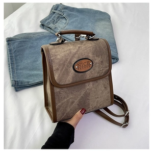 Close-up of vintage brown suede crossbody bag with leather trim and NICE FASHION plaque