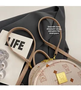 Detail of adjustable strap and bear print on off-white round leather backpack