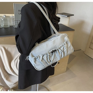 Detail view of the drawstring ruched side and textured fabric of the blue shoulder bag