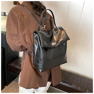 Detail of black leather backpack with silver rotating buckle and polished texture on model