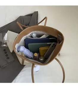Vista dall'alto dell'interno della borsa tote con laptop e oggetti di uso quotidiano
