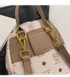 Close-up of golden metal D-ring and lobster clasp on textured beige leather backpack