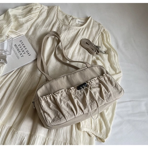 Detail of beige pleated shoulder bag with drawstring pocket and detachable long strap
