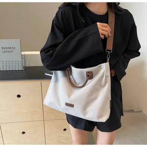 Detail of nylon tote bag with brown leather handles and wide shoulder strap