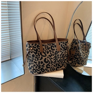 Close-up of leopard print tote bag featuring brown leather handles and side drawstrings