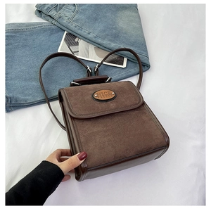 Detail of dark brown faux suede backpack with oval metal plaque and smooth leather trim
