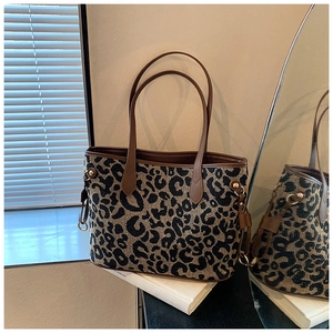 Detail of leopard print tote bag with brown leather trim and metallic gold hardware