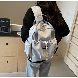 Close-up of lightweight nylon backpack featuring double zippers and drawstring front pocket