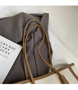 Dettagli dei robusti spallacci su una borsa tote minimalista in pelle a grana litchi